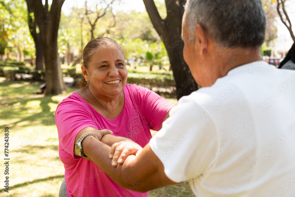 Adult woman enjoys exercise routine accompanied by her husband. She looks confident as she performs a squat. 