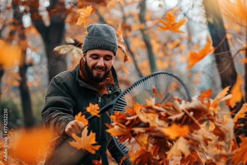 man with a fan rake picking up fallen leaves in autumn