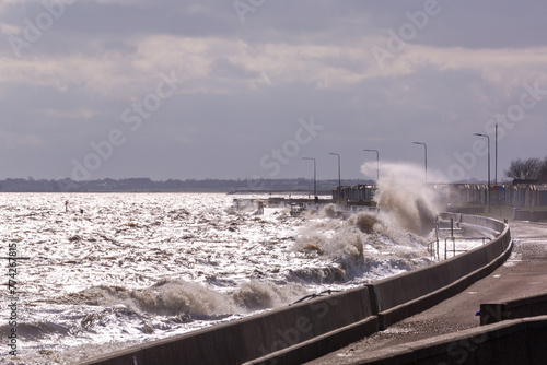 Rough high tide or spring tide on Dovercourt beach, Harwich with larges waves hitting against the sea wall completely covering the sandy beaches  photo