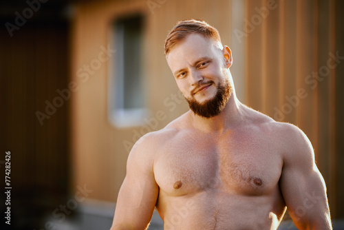 Foto Ironic athlete with goatee without shirt outdoors near wooden rural house outside city
