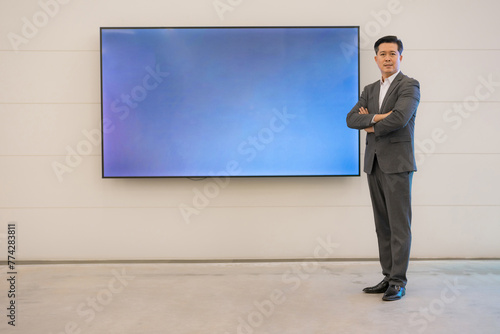 Confident businessman standing by digital display