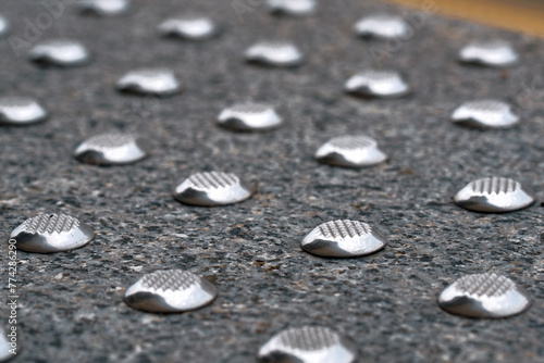 Warning, hazard tactile indicator closeup. Stainless steel tactile ground surface indicator, truncated cone installed on the ground or floor surface to provide cues for blind or vision-impaired people photo