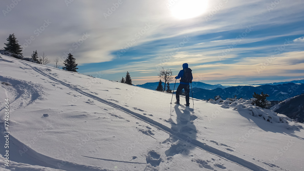 Man with snowshoes in snow covered meadow on way to Hochanger, Muerzsteg Alps, Styria, Austria. Panoramic view of snow capped mountain peaks Hochschwab massif. Winter wonderland remote Austrian Alps Man with snowshoes in snow covered meadow on way to Hochanger, Muerzsteg Alps, Styria, Austria. Panoramic view of snow capped mountain peaks Hochschwab massif. Winter wonderland remote Austrian Alps