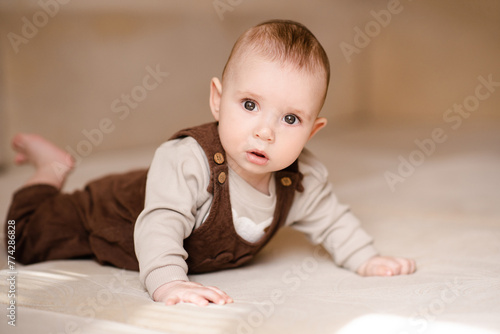 Cute baby boy 3-4 months old crawling in bed looking at camera close up. Childhood. © morrowlight