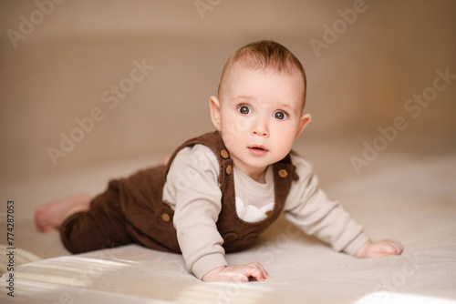 Cute baby boy 3-4 months old crawling in bed looking at camera close up. Childhood. © morrowlight