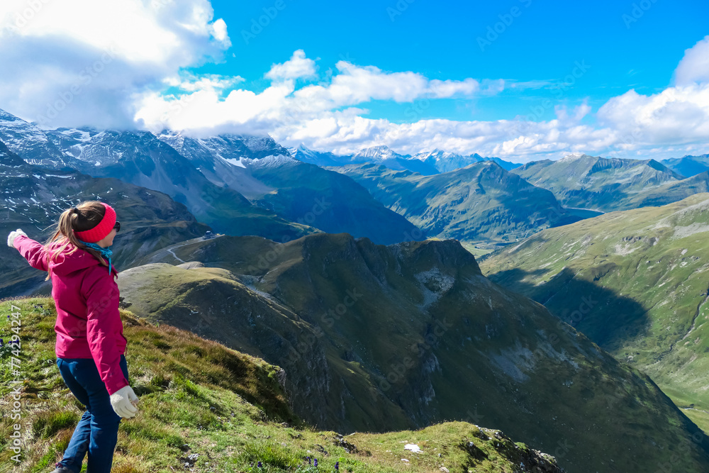Hiker woman on top of mount Greilkopf with scenic view of majestic mountain peaks of Glocker group, High Tauern National Park, Carinthia Salzburg, Austria. Wanderlust at Hagener Huette, Austrian Alps