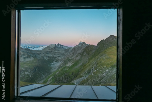 Panoramic sunset view from cottage window of majestic mountain peaks in High Tauern National Park, Salzburg Carinthia border, Austria. Tranquil atmosphere in remote Austrian Alps.Hagener Huette photo