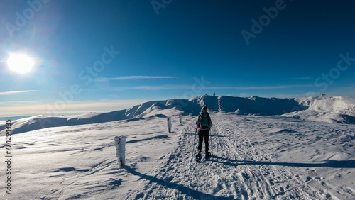 Woman in snowshoes on the way to majestic summit peak Grosser Speikogel in Kor Alps, Lavanttal Alps, Carinthia Styria, Austria. Winter wonderland in Austrian Alps. Idyllic ski touring hiking trail photo