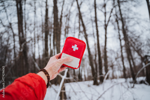 First aid kit in the river against the background of trees, survival in the wild forest, red first aid kit.