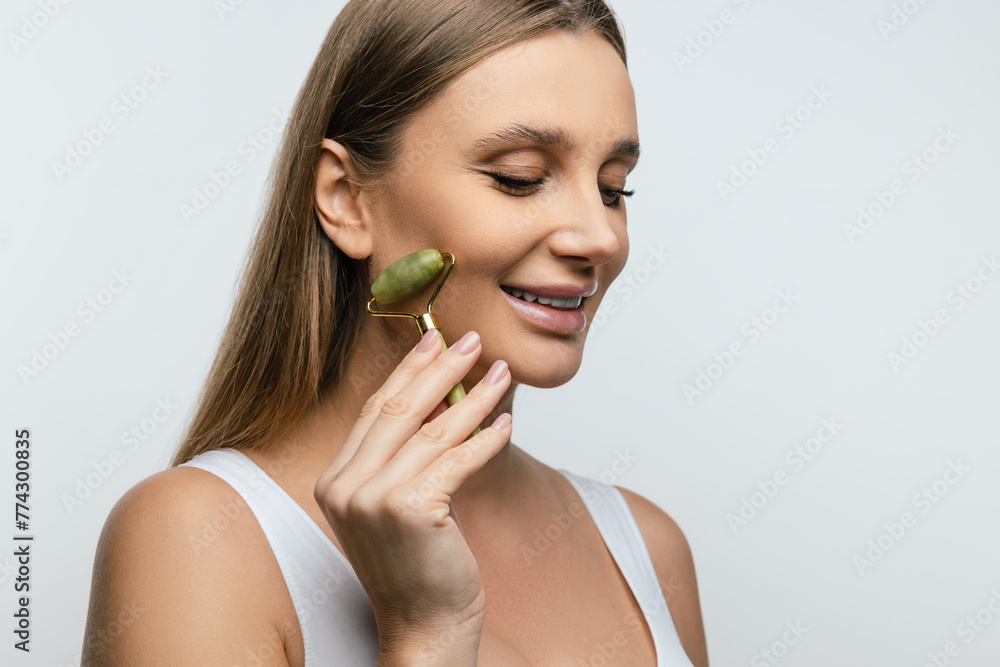 Cute young woman making face massage with a roller Cute young woman making face massage with a roller