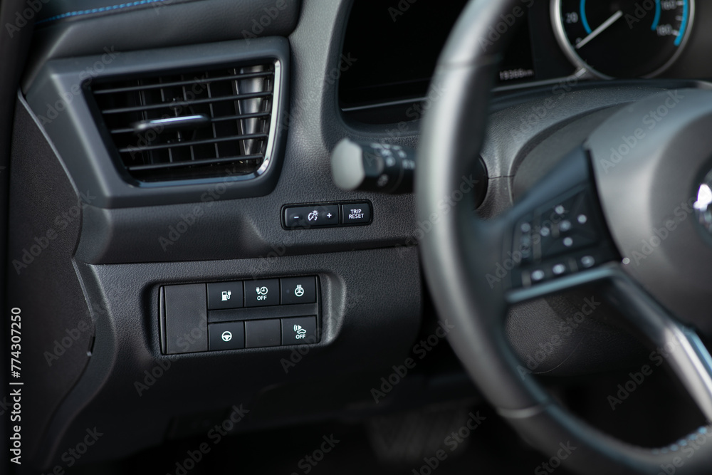 Cruise control, speed limit and volume buttons on modern car steering wheel, interior details. Buttons on the steering wheel. Electric car with adaptive cruise control radar