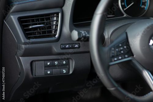 Cruise control, speed limit and volume buttons on modern car steering wheel, interior details. Buttons on the steering wheel. Electric car with adaptive cruise control radar