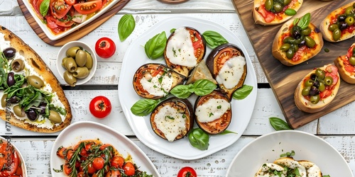 Italian vegetarian platter on a white wooden table in a restaurant showcasing caprese salad, eggplant Parmesan, bruschetta, and olives. Concept Italian Cuisine, Vegetarian Platter