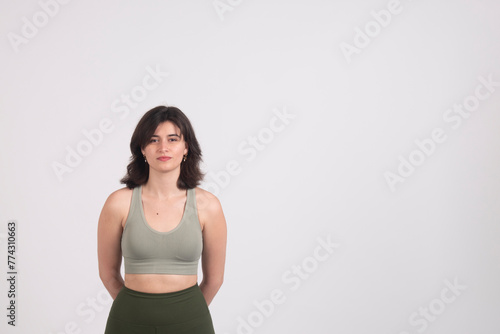 Confident young woman in casual attire standing against a white background with copy space.