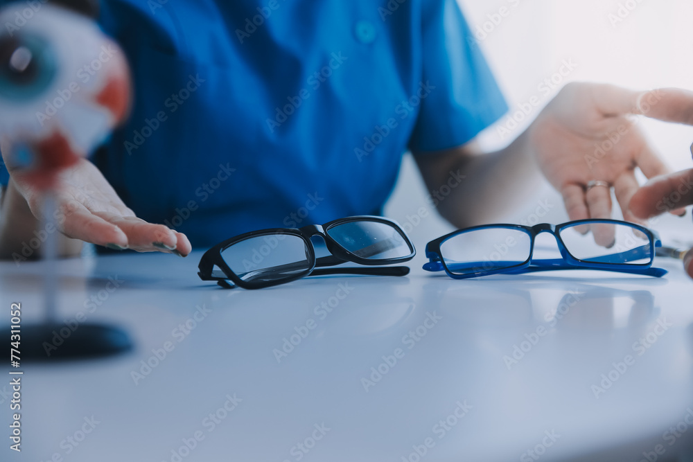 Close-up of Asian female doctor talking with elderly patient showing eyeball model and explaining eye disease in hospital Close-up of Asian female doctor talking with elderly patient showing eyeball model and explaining eye disease in hospital