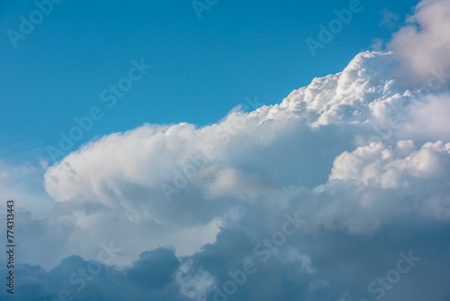 Scenic view to huge dramatic white clouds in blue sky. Nature background of fluffy cloudiness. Beautiful minimalist cloudscape. Nature texture of cloudy skies. Minimal skyscape in changeable weather.