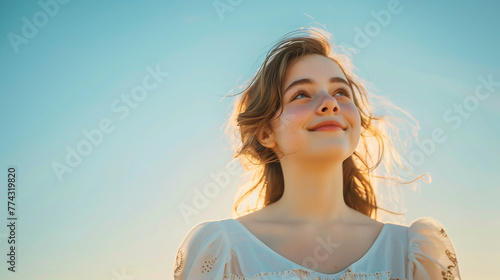 Ethereal lighting similar to fine art portraiture, capturing the joy and confidence of a stylish 19-year-old girl against a solid sky blue background photo