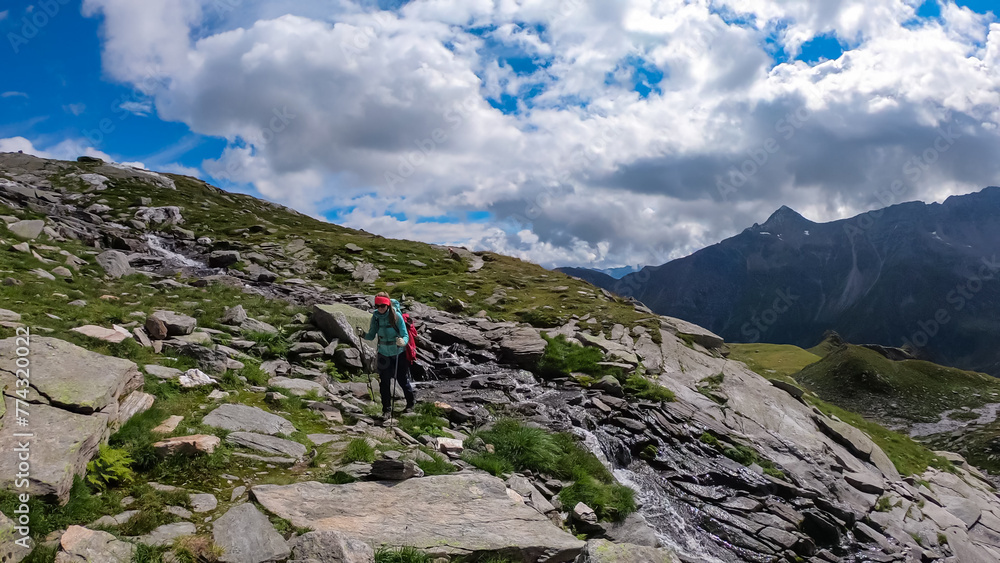 Hiker woman on alpine meadow with panoramic view of majestic mountain summits in High Tauern National Park, Carinthia, Austria. Idyllic hiking trail in Austrian Alps. Wanderlust paradise Mallnitz