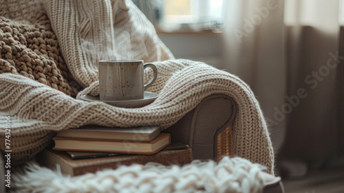 Books, mug, and knitted throw on armchair.