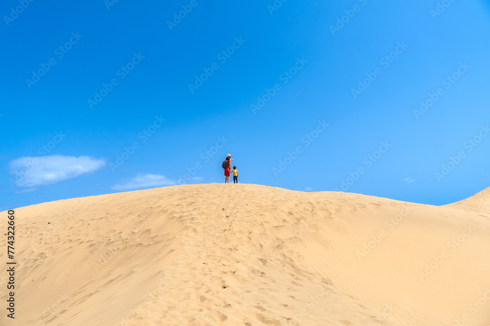 Mother and child walking in the dunes of Maspalomas in summer, Gran Canaria, Canary Islands Mother and child walking in the dunes of Maspalomas in summer, Gran Canaria, Canary Islands