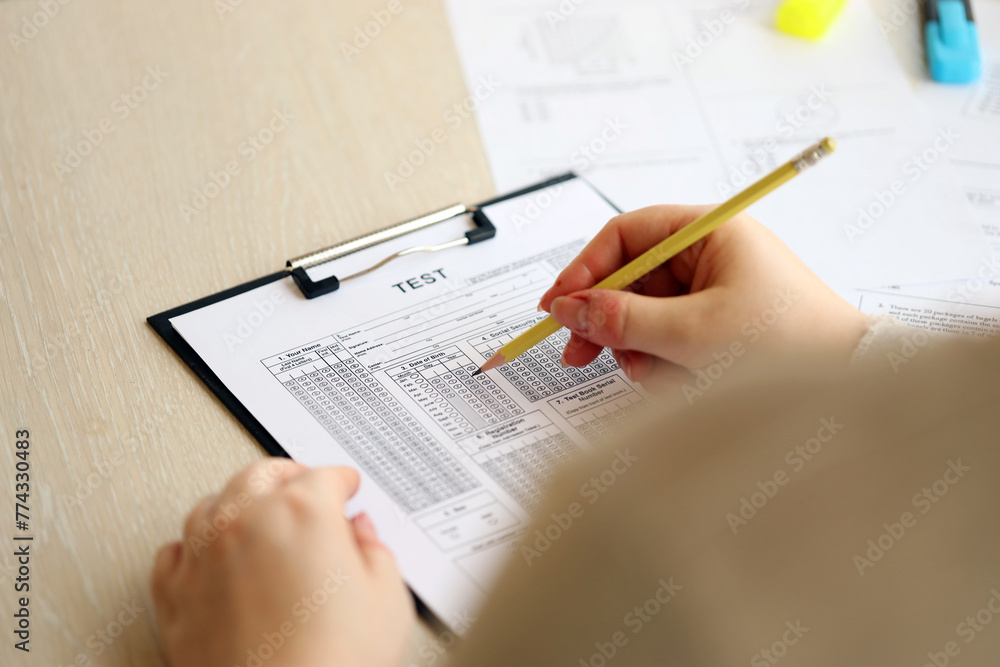 Female student hands testing in exercise and taking fill in exam paper sheet with pencil at school test room, education concept Female student hands testing in exercise and taking fill in exam paper sheet with pencil at school test room, education concept