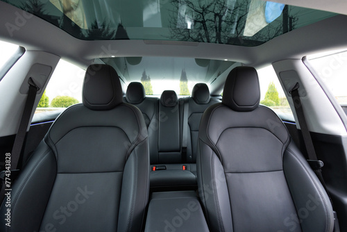Panoramic glass sun roof in the modern electric car interior. The view from the empty car with seats. Luxury car leather seats. Interior of new clean expensive car. Passenger seats with leather © uflypro