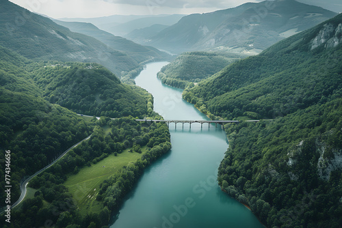 an aerial view of a river surrounded by mountains and greenery, with a bridge in the middle of the river and a bridge in the middle of the river.