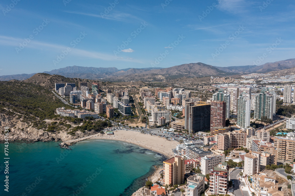 Aerial drone photo of the town of Benidorm in Spain in the summer time showing the beach known locally as Playa de Finestrat and hotels and apartments around the small beach