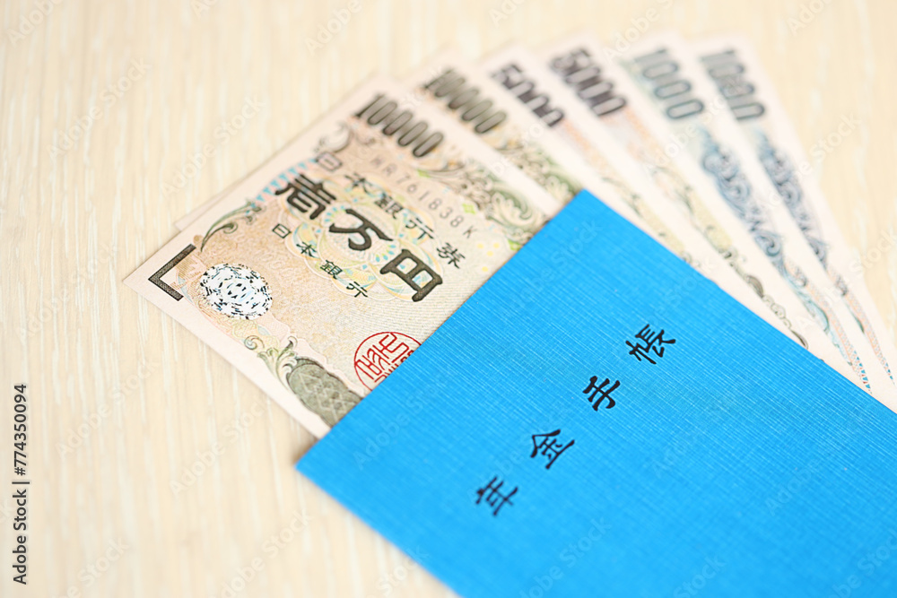 Japanese pension insurance book on table with yen money bills. Blue book for japan pensioners close up Japanese pension insurance book on table with yen money bills. Blue book for japan pensioners close up
