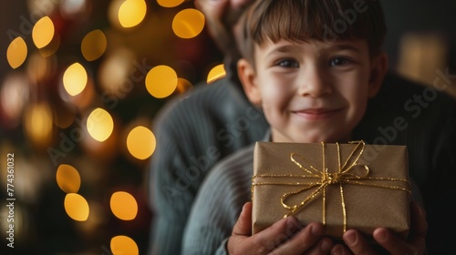 Young Boy Holding Present By Christmas Tree