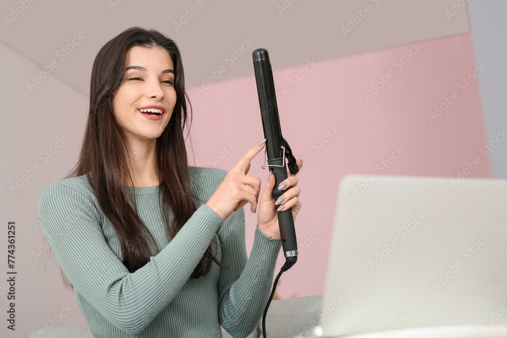 Beautiful young happy female blogger with laptop and flattening iron recording video at home Beautiful young happy female blogger with laptop and flattening iron recording video at home