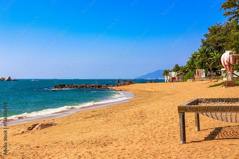 View of the shore of the South China Sea with a sandy beach and large rocks. Sanya, China.