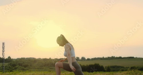 Young woman doing yoga in nature, wearing a white top and olive-colored shorts.