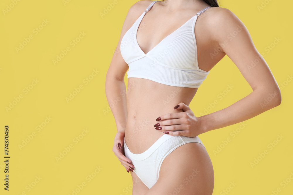 Young woman in white underwear on yellow background