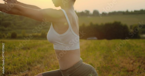 Young woman doing yoga in nature, wearing a white top and olive-colored shorts.