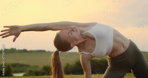 Young woman doing yoga in nature, wearing a white top and olive-colored shorts.