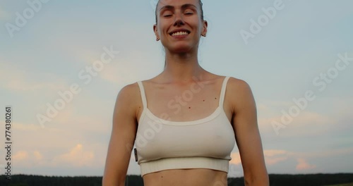 Young woman doing yoga in nature, wearing a white top and olive-colored shorts.