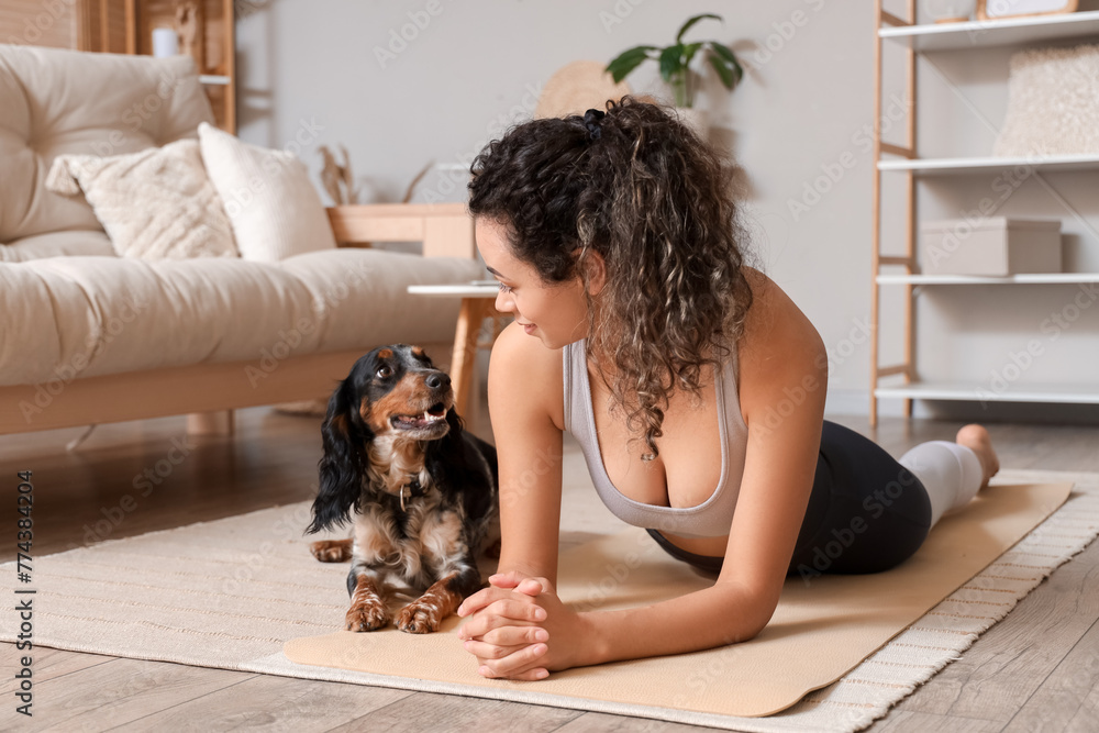 Sporty young African-American woman with cocker spaniel lying on yoga mat at home Sporty young African-American woman with cocker spaniel lying on yoga mat at home
