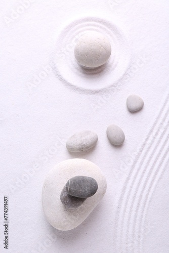 Photography Zen garden stones on white sand with pattern, flat lay