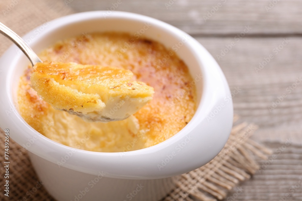 Taking delicious creme brulee with spoon from bowl at table, closeup Taking delicious creme brulee with spoon from bowl at table, closeup
