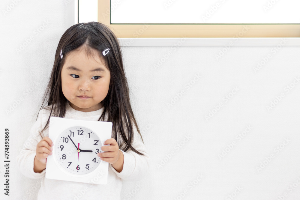 時計を持つ落ち込んだ女の子（3歳、日本人）