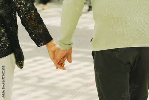 Two People Holding Hands Walking Down a Street