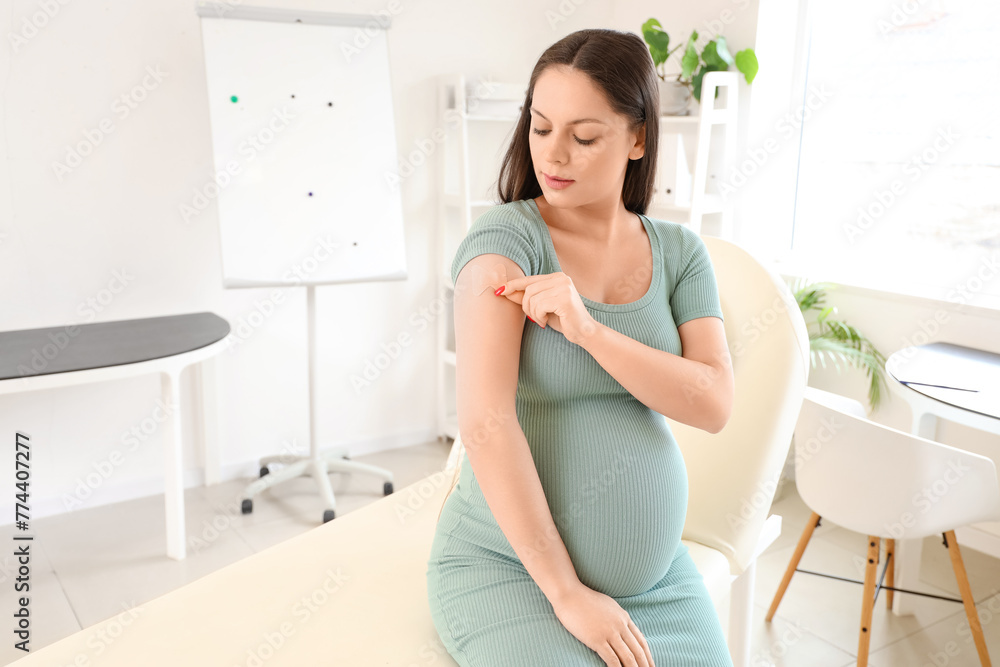 Young pregnant woman with medical patch after vaccination in clinic Young pregnant woman with medical patch after vaccination in clinic