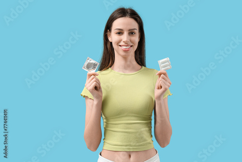 Beautiful young woman with condom and vaginal suppositories on blue background © Pixel-Shot