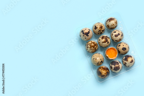 Plastic holder with fresh quail eggs on blue background
