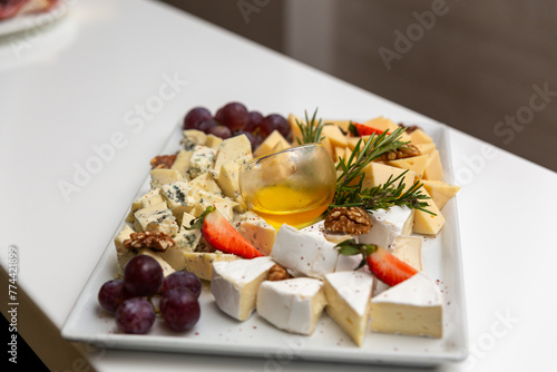 Cheese plate with fruit and spices on a white table.