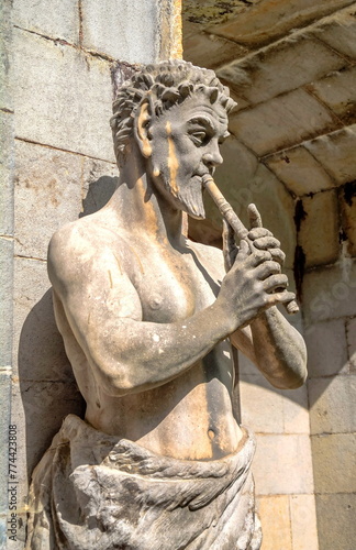 An ancient statue depicting the ancient deity Fawn (Satyr) playing the flute