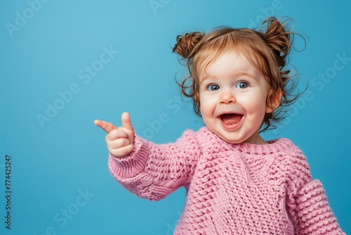 adorable little toddler pointing hr finger at something in pink knitted sweater 