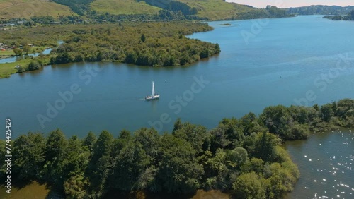 Aerial: Boat sailing on calm Lake Rotoiti, Rotorua, Bay of Plenty, New Zealand. photo