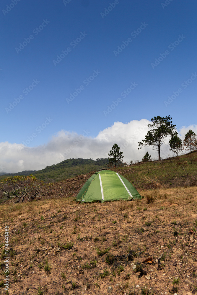 Green hiking tent in campsite in the mountain during dry season or summer with beautiful blue sky. Outdoors concept.